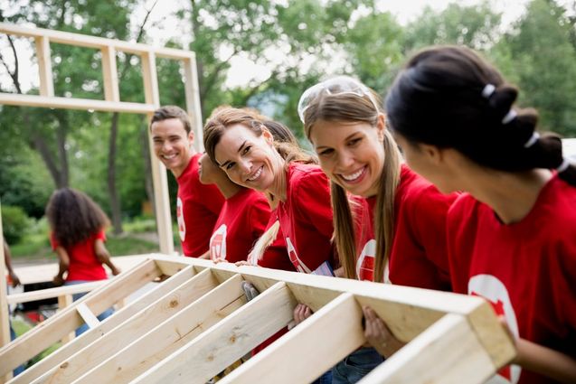 Un grupo de voluntarios con camisetas rojas monta una estructura de madera